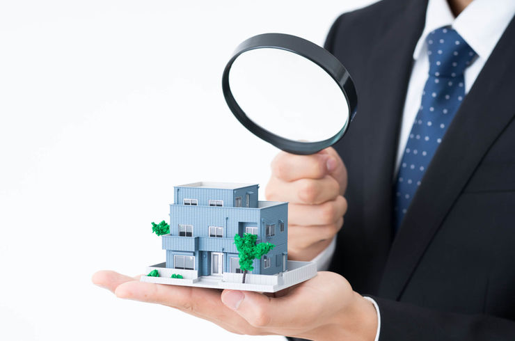 虫眼鏡で模型を見る男性